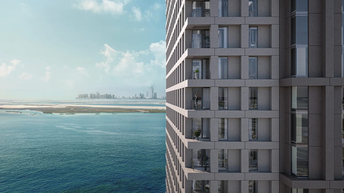 Residential tower facade of Abu Dhabi co-living project overlooking water and the city skyline