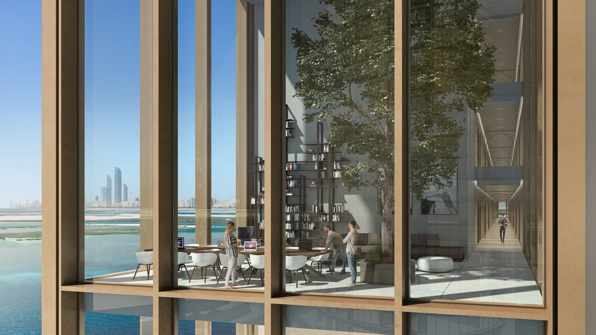 Interior amenity space overlooking the Abu Dhabi waterfront through tall glazing and planted edges