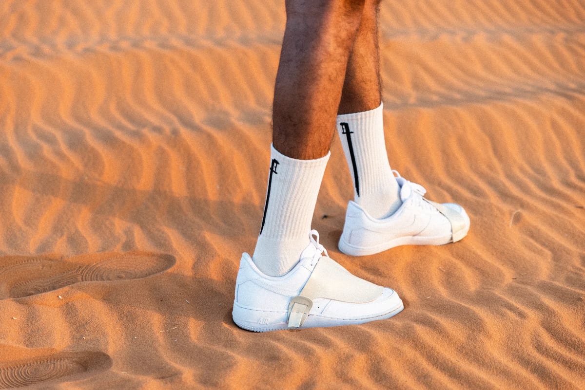 White Nike footwear walking across wind-shaped desert sand in a Saudi product campaign