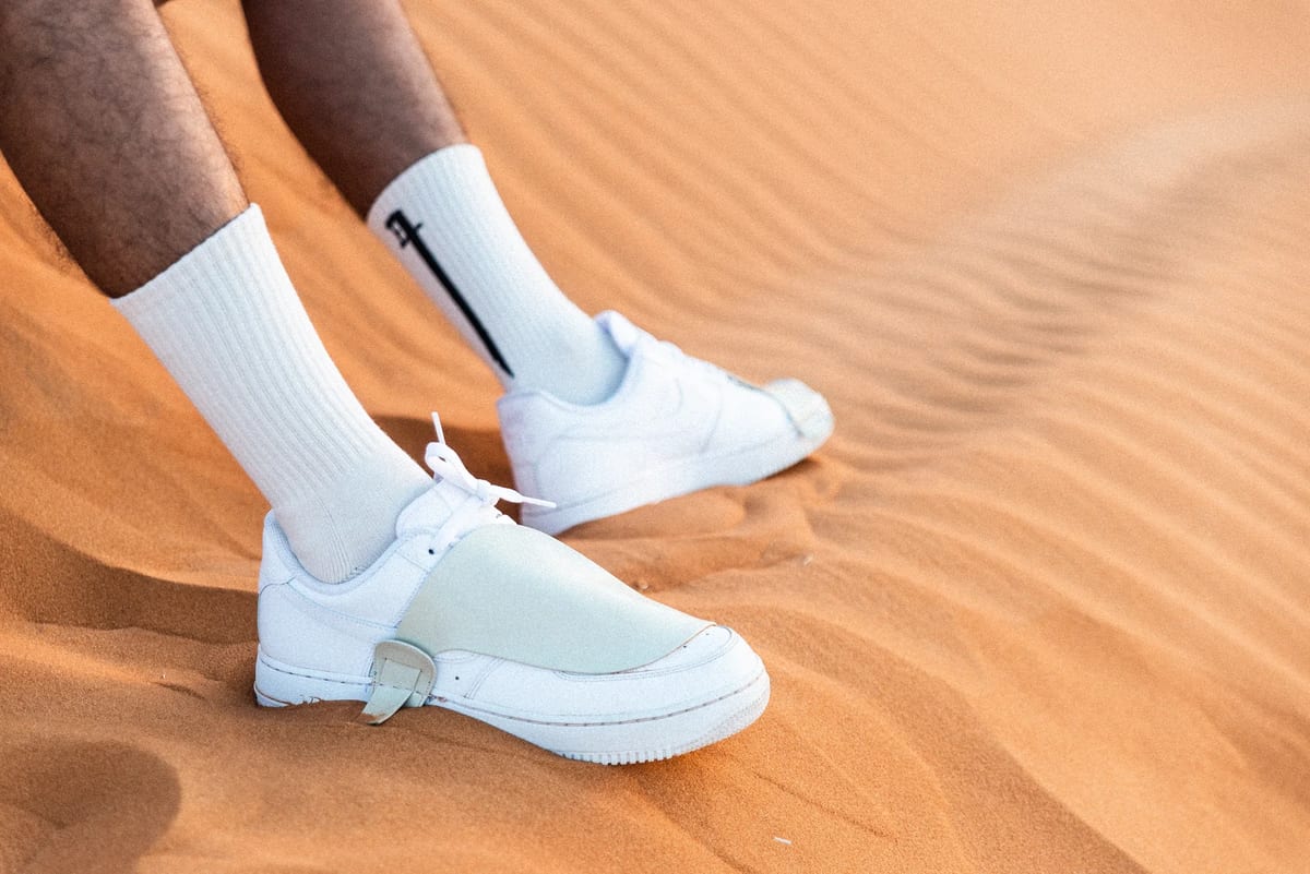 Close detail of white Nike shoe and sock on orange desert dunes